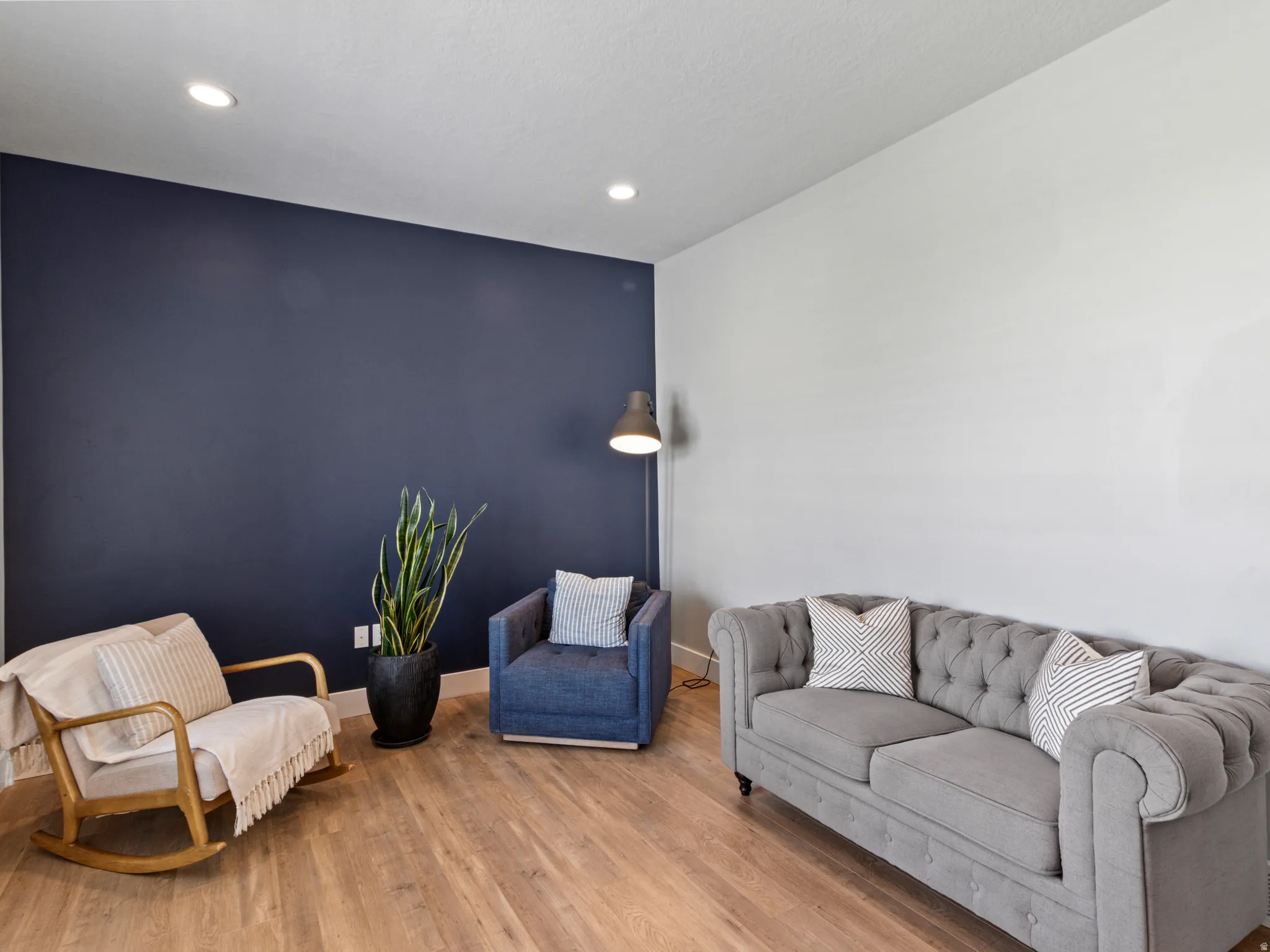 Recessed ceiling lighting, wood-finish flooring, and a contrasting accent wall