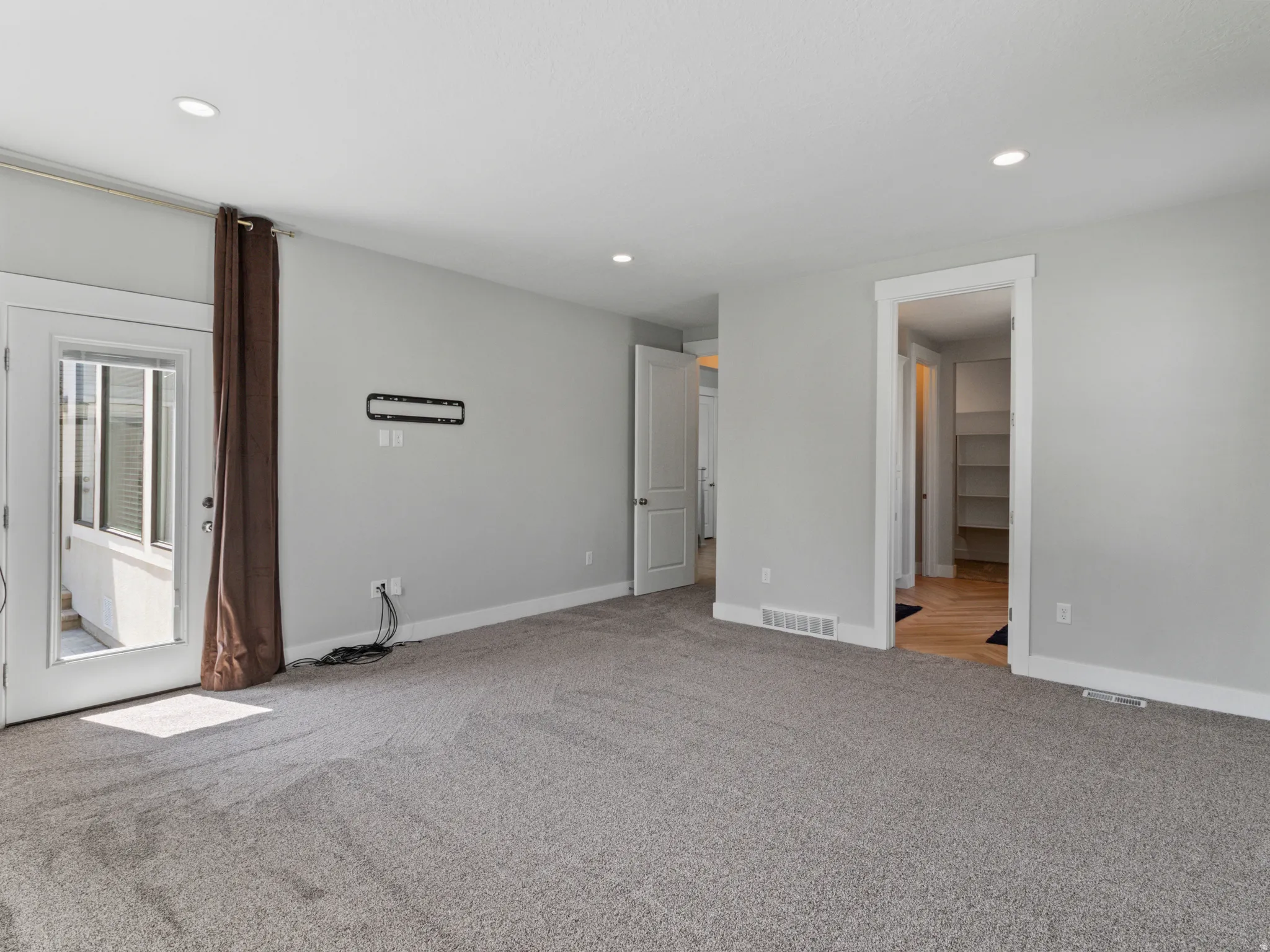 Spacious primary living area with neutral wall finishes, recessed ceiling lighting, and direct access to outdoor space