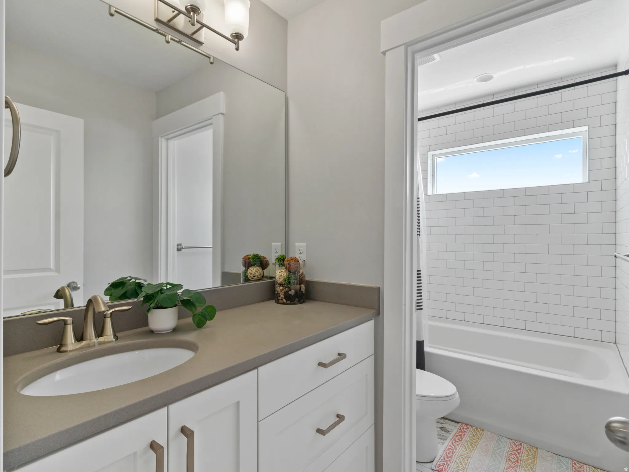 Bathroom featuring a built-in vanity with an undermount sink, a neutral-toned countertop, and white cabinetry with bronze hardware
