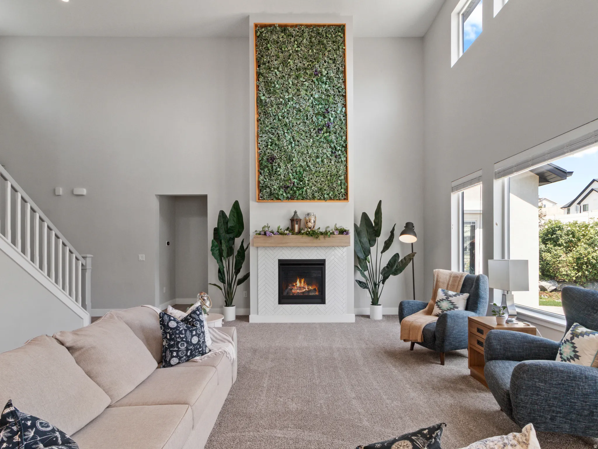 Soaring ceilings with upper windows and a statement fireplace featuring a herringbone tile surround