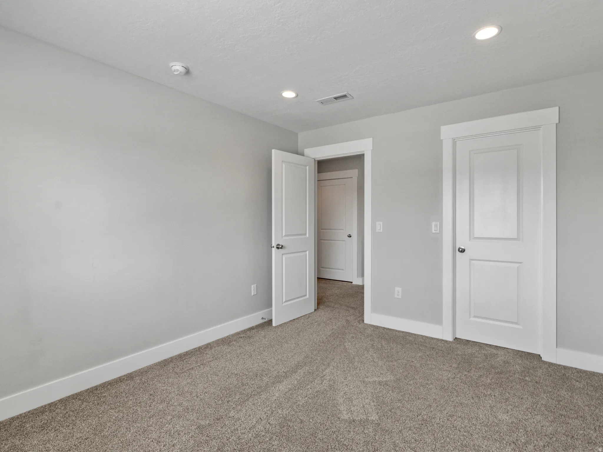 Neutral-toned carpeting, white trim, recessed lighting, and panel doors