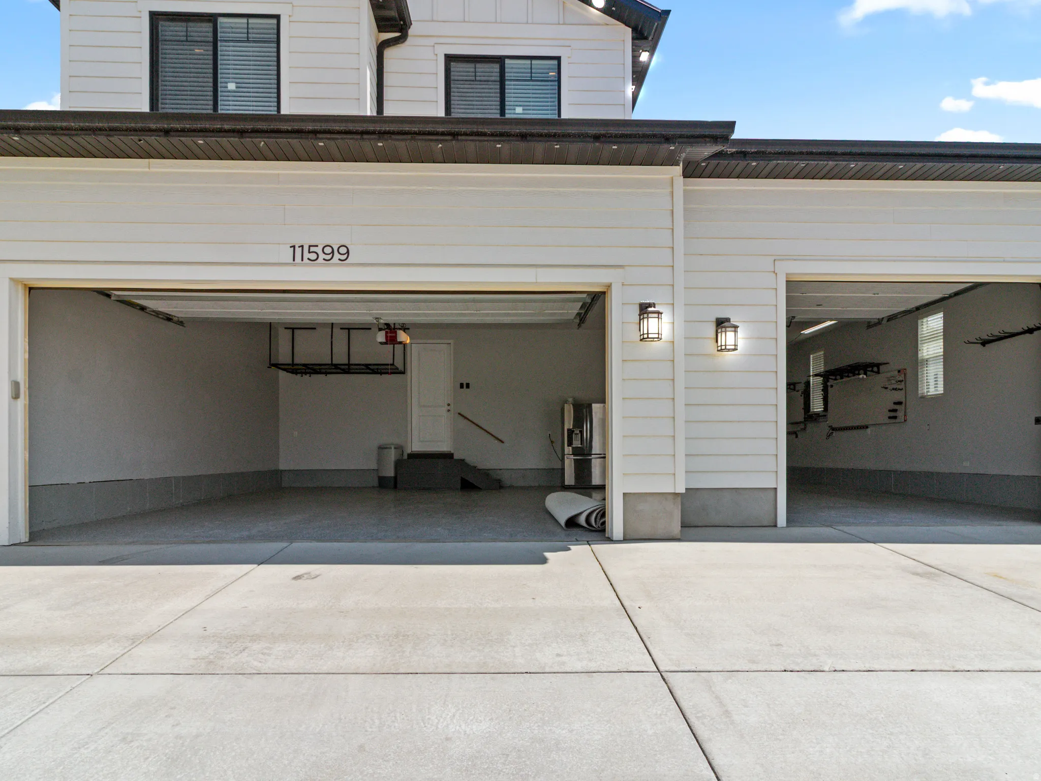 5-car garage with concrete flooring, exterior wall sconces, and white siding