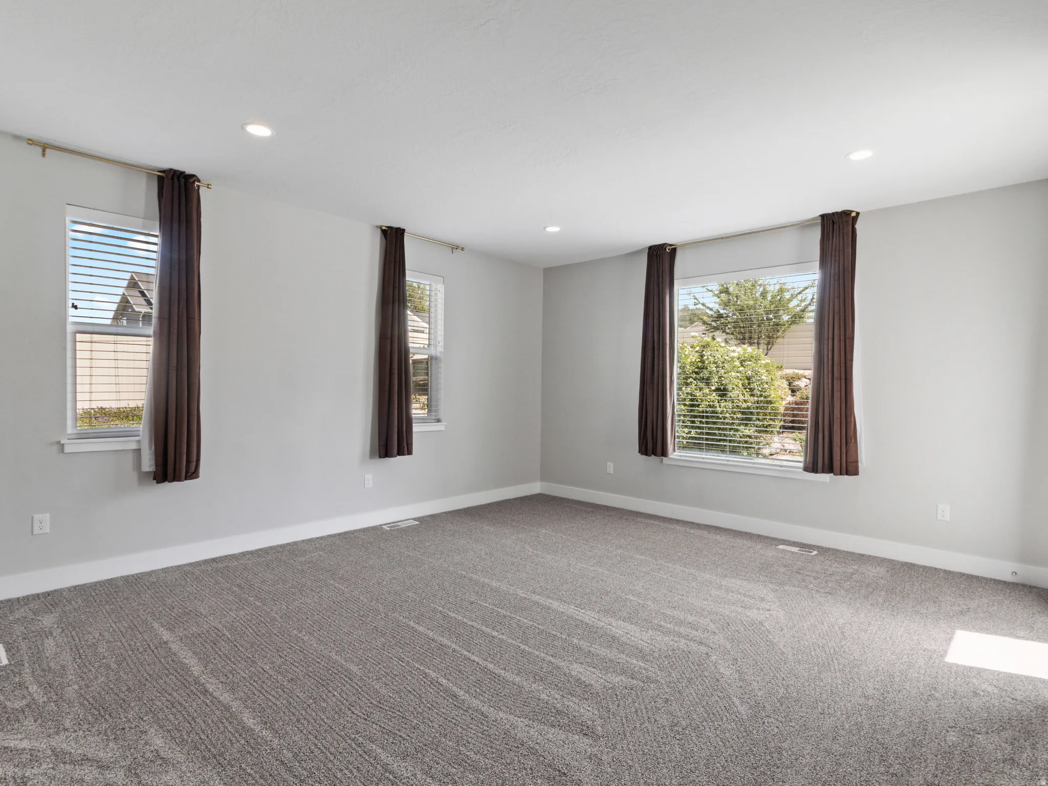 Recessed lighting throughout, gray wall paint, and gray patterned carpeting