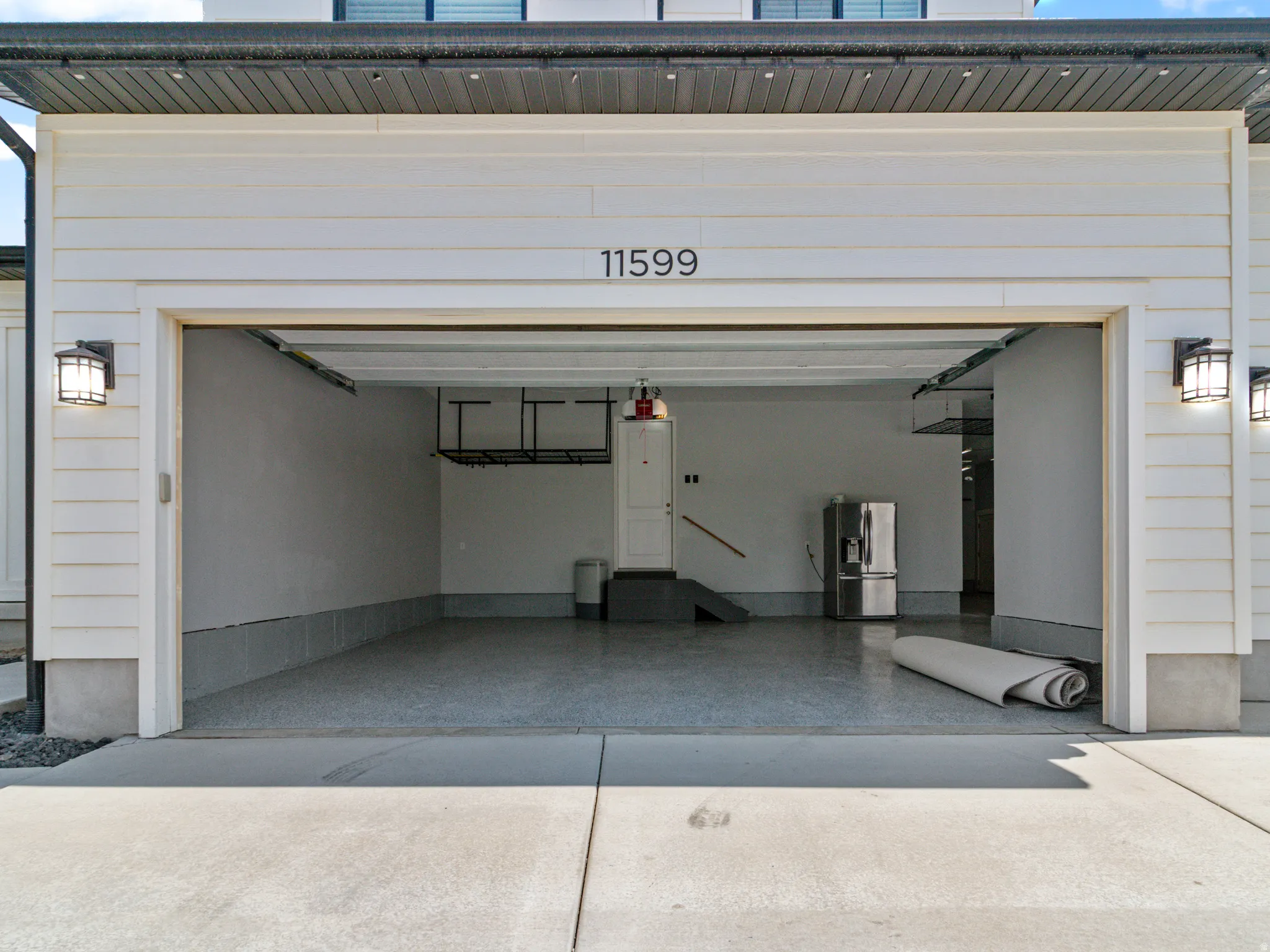 Garage featuring a concrete floor, overhead storage racks, and wall-mounted exterior lighting fixtures