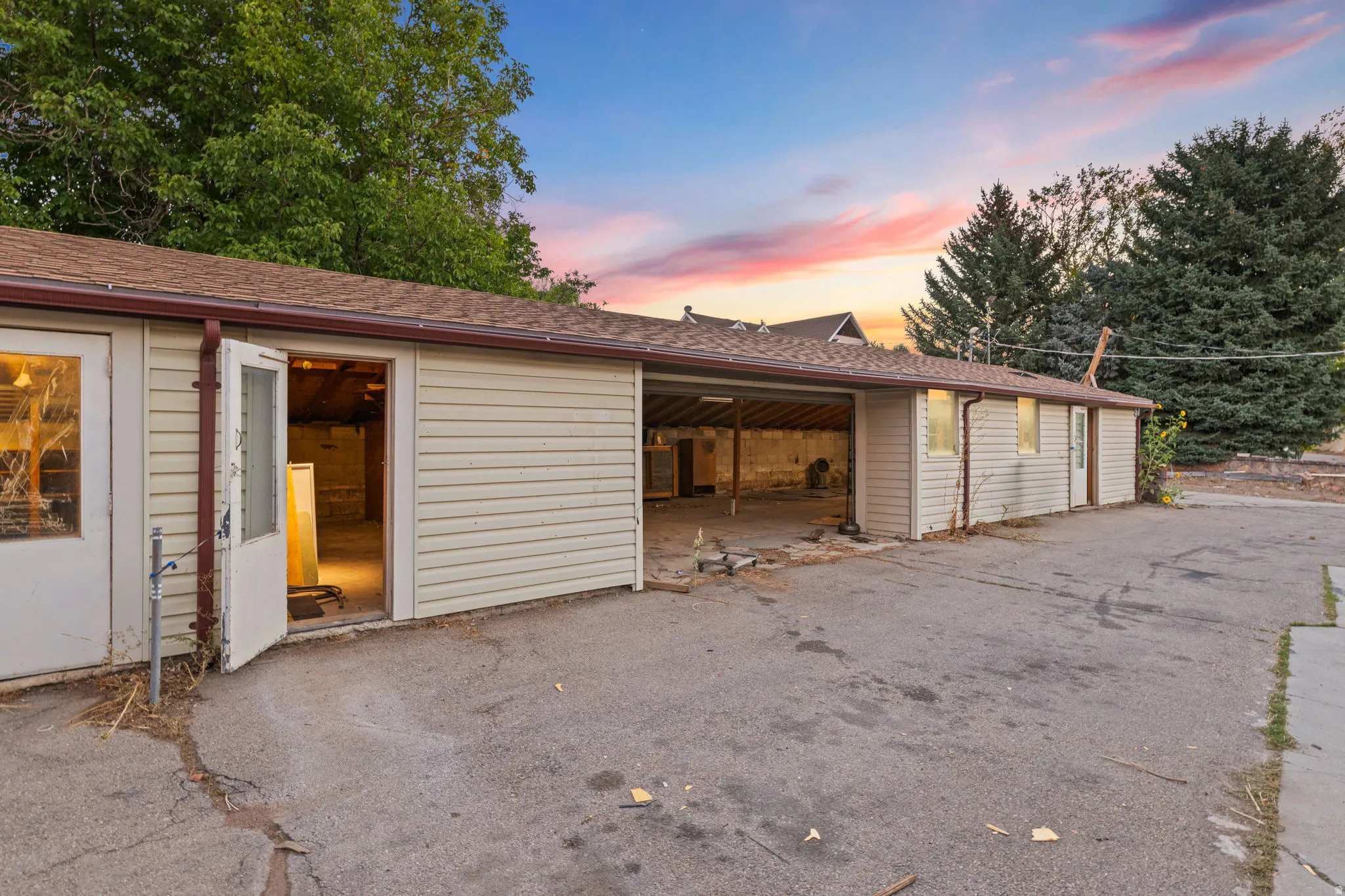 Detached outbuilding with multiple access points, covered parking area, and vinyl siding