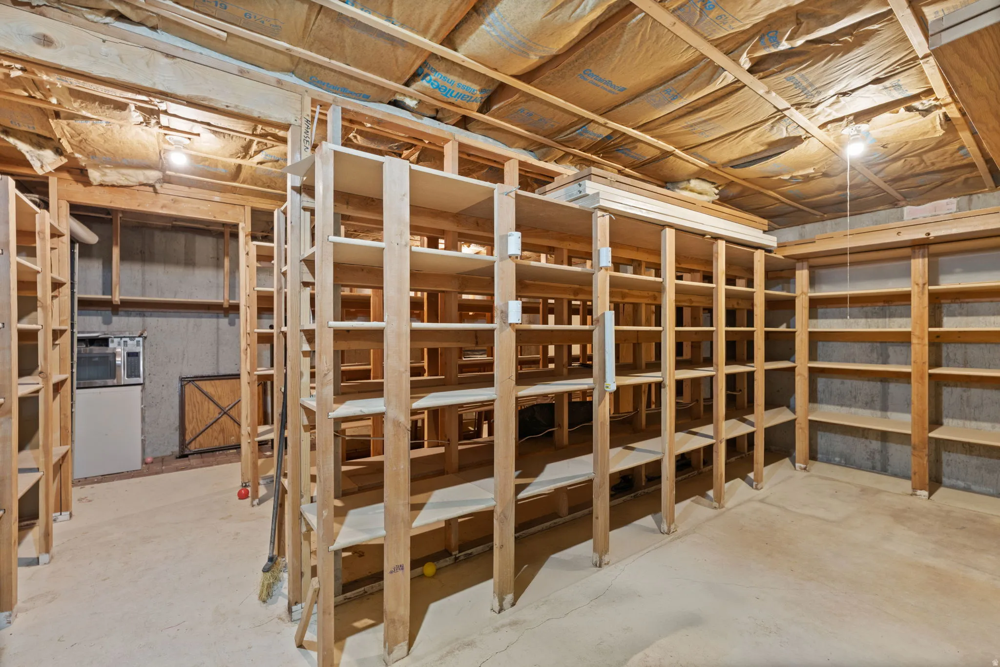 Extensive built-in shelving, exposed wood ceiling beams, and concrete flooring