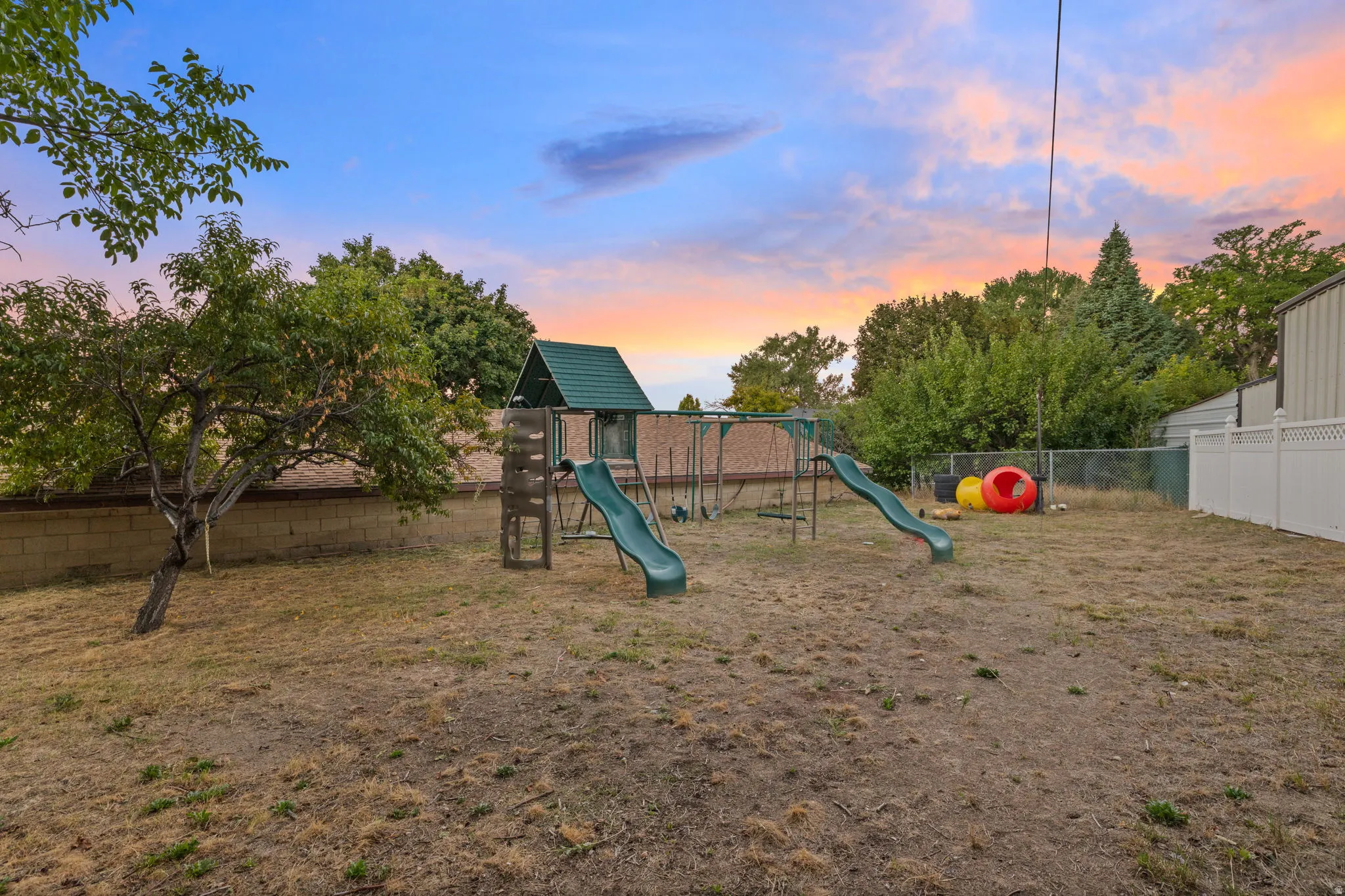 Expansive backyard featuring mature trees, a block wall, and a vinyl fence