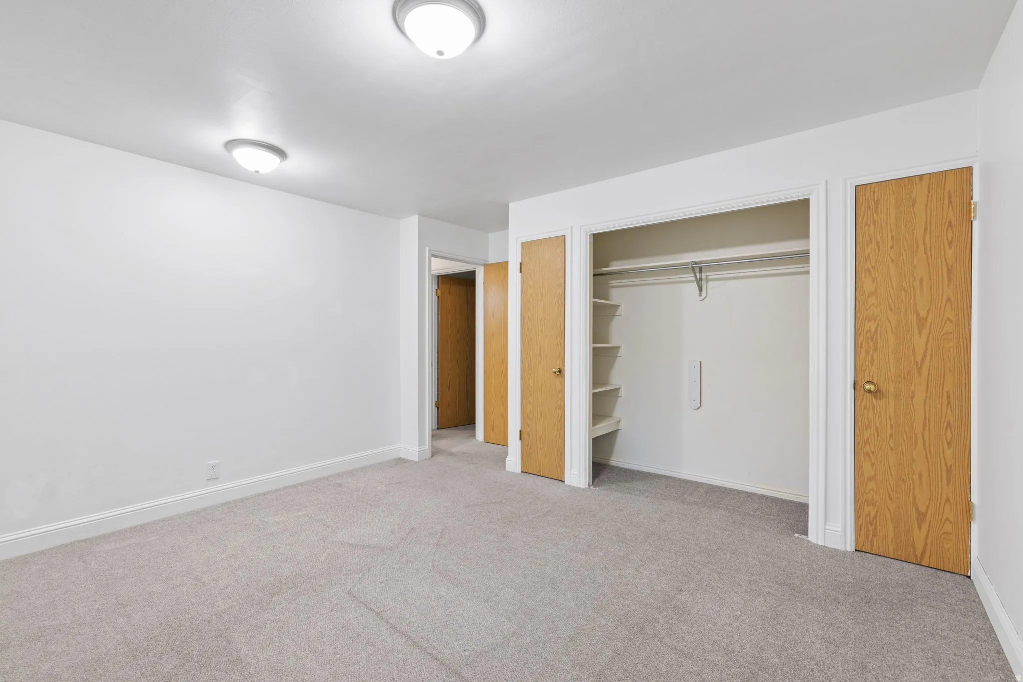 Plush carpeting, recessed closet with shelving, two panel doors, and two flush-mount ceiling lights
