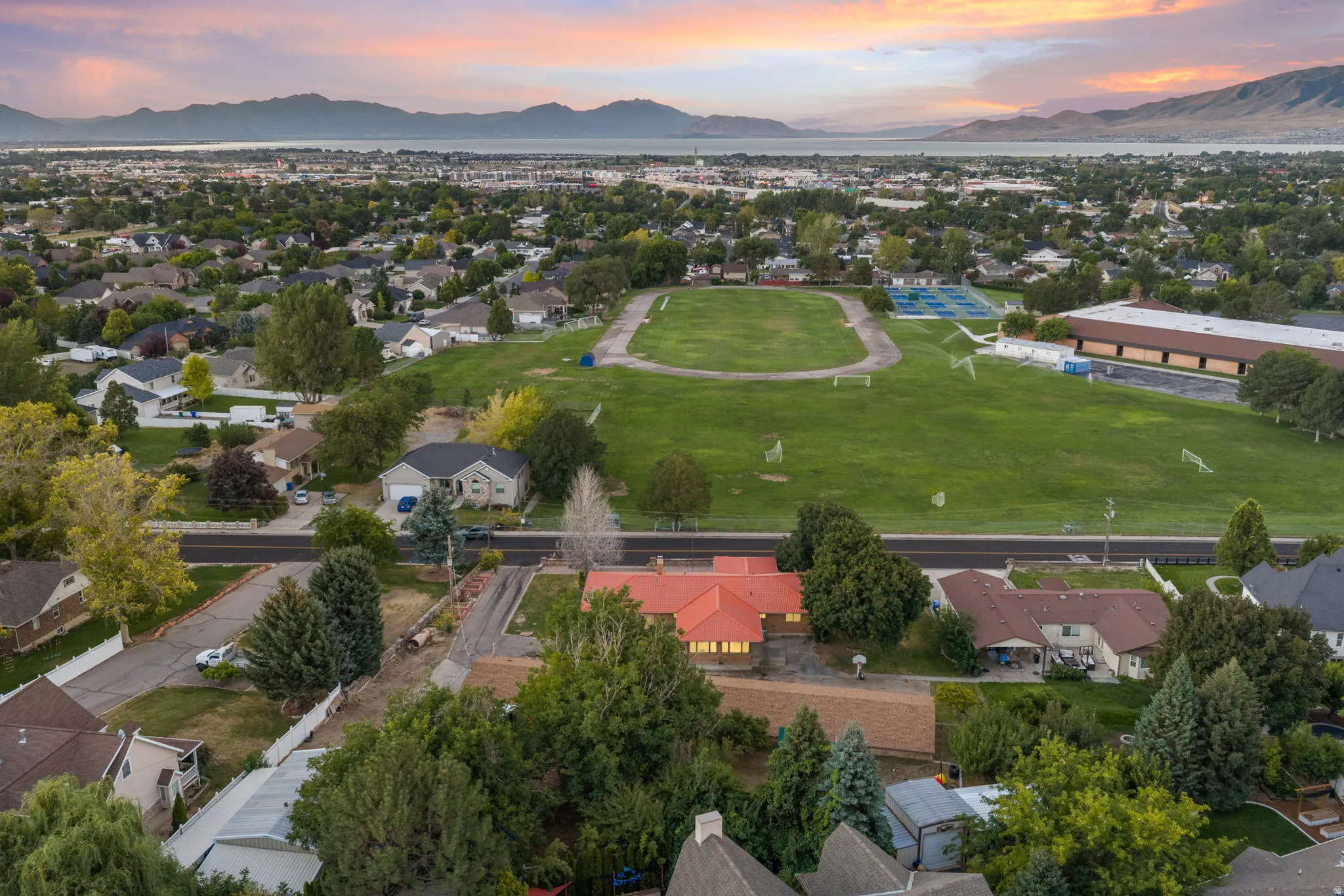 Aerial perspective showcasing the residential neighborhood, expansive green spaces, and distant mountain and water features