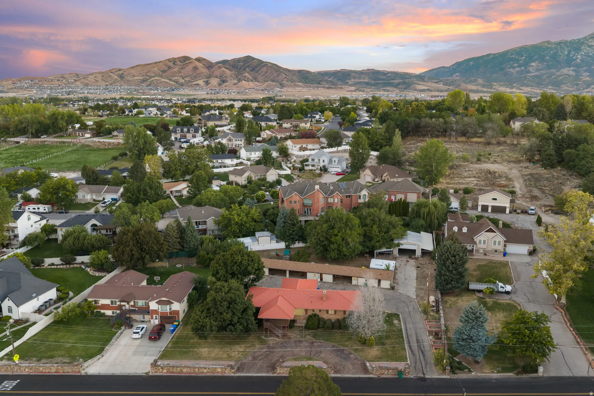Residential neighborhood featuring varied architectural styles and mature trees, set against a mountain backdrop