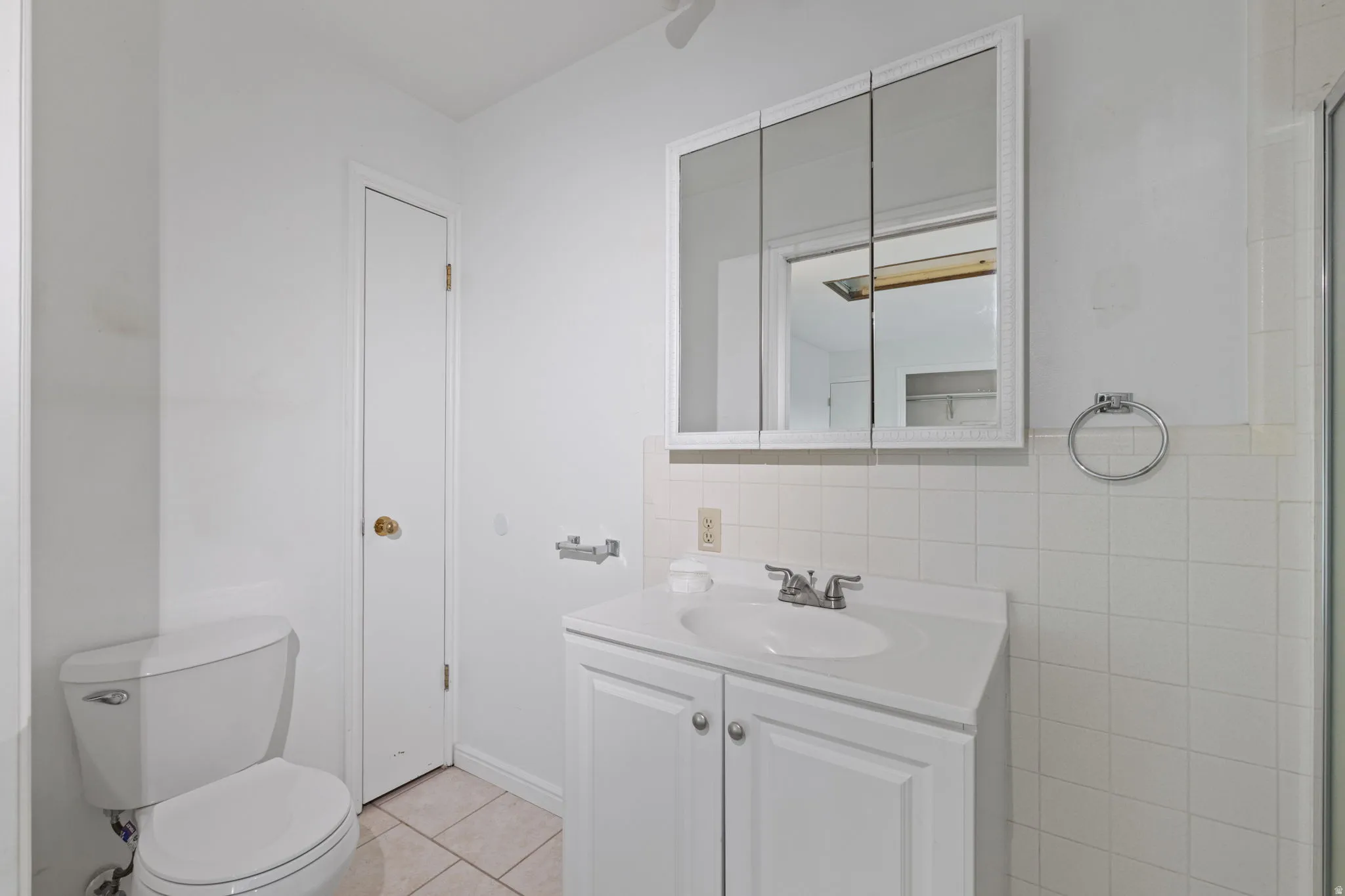 Recessed medicine cabinet, white vanity with integrated sink, chrome faucet, and white wall tile