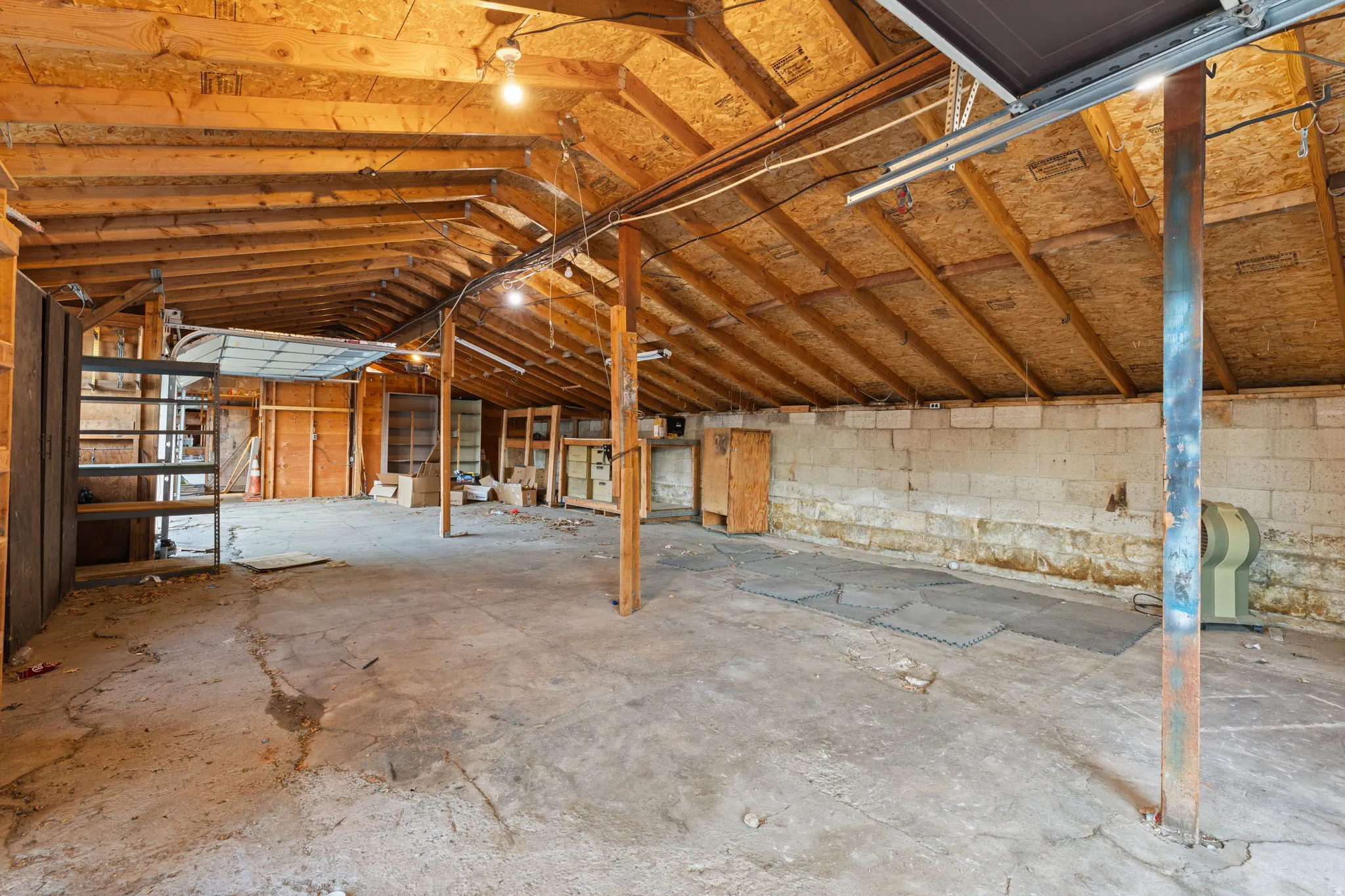 Exposed wood beam ceiling, concrete floor, block wall construction, built-in shelving, and overhead lighting