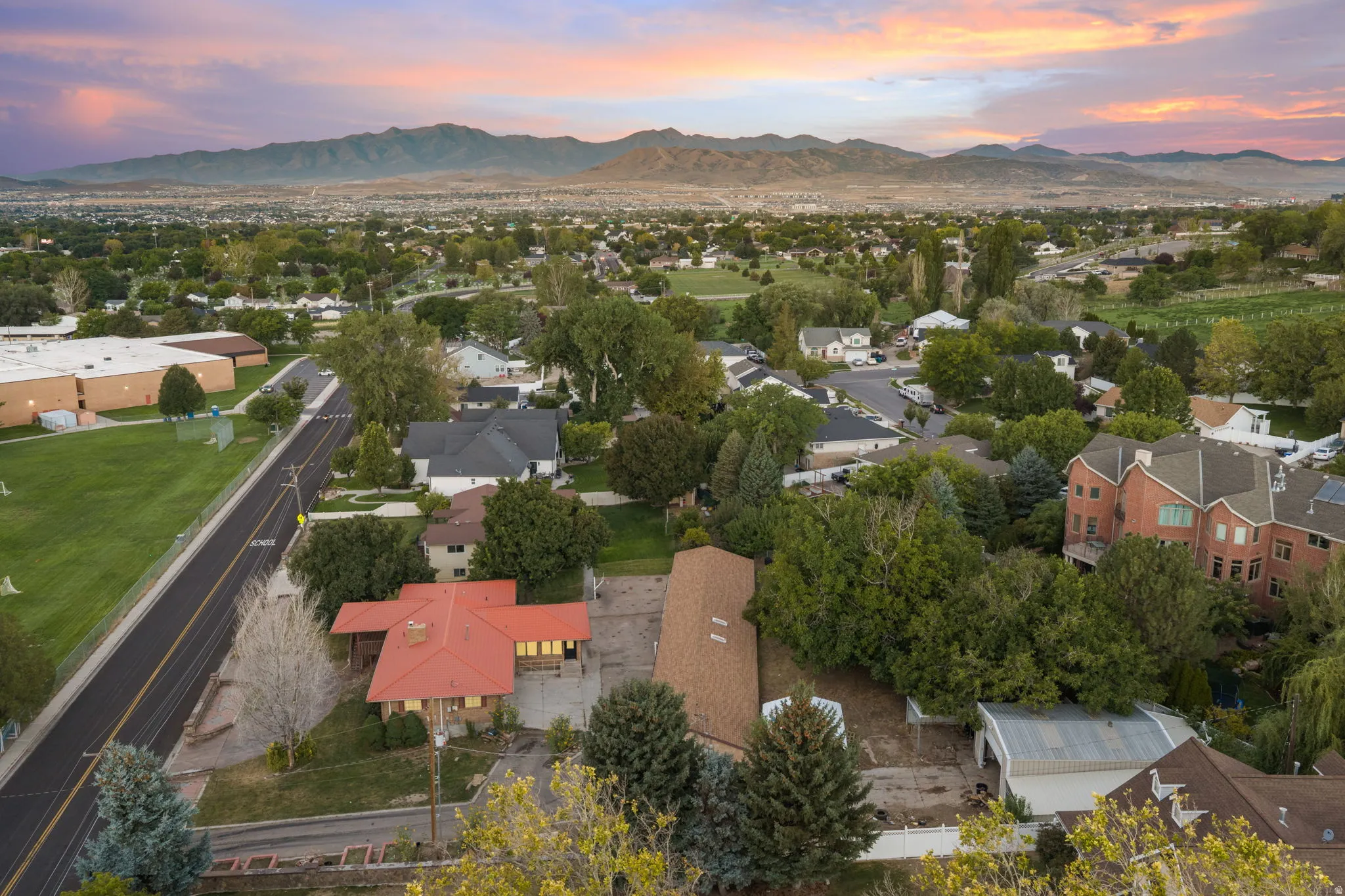Residential neighborhood with mature trees, mountain backdrop, and adjacent green space
