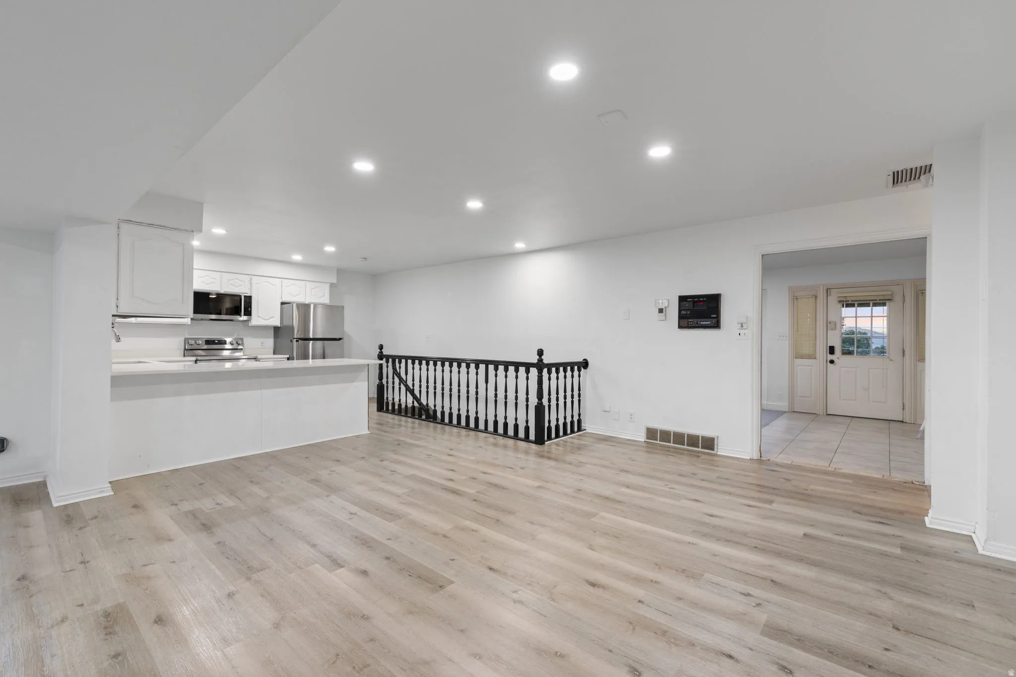Contemporary kitchen with white cabinetry, stainless steel appliances, and a breakfast bar