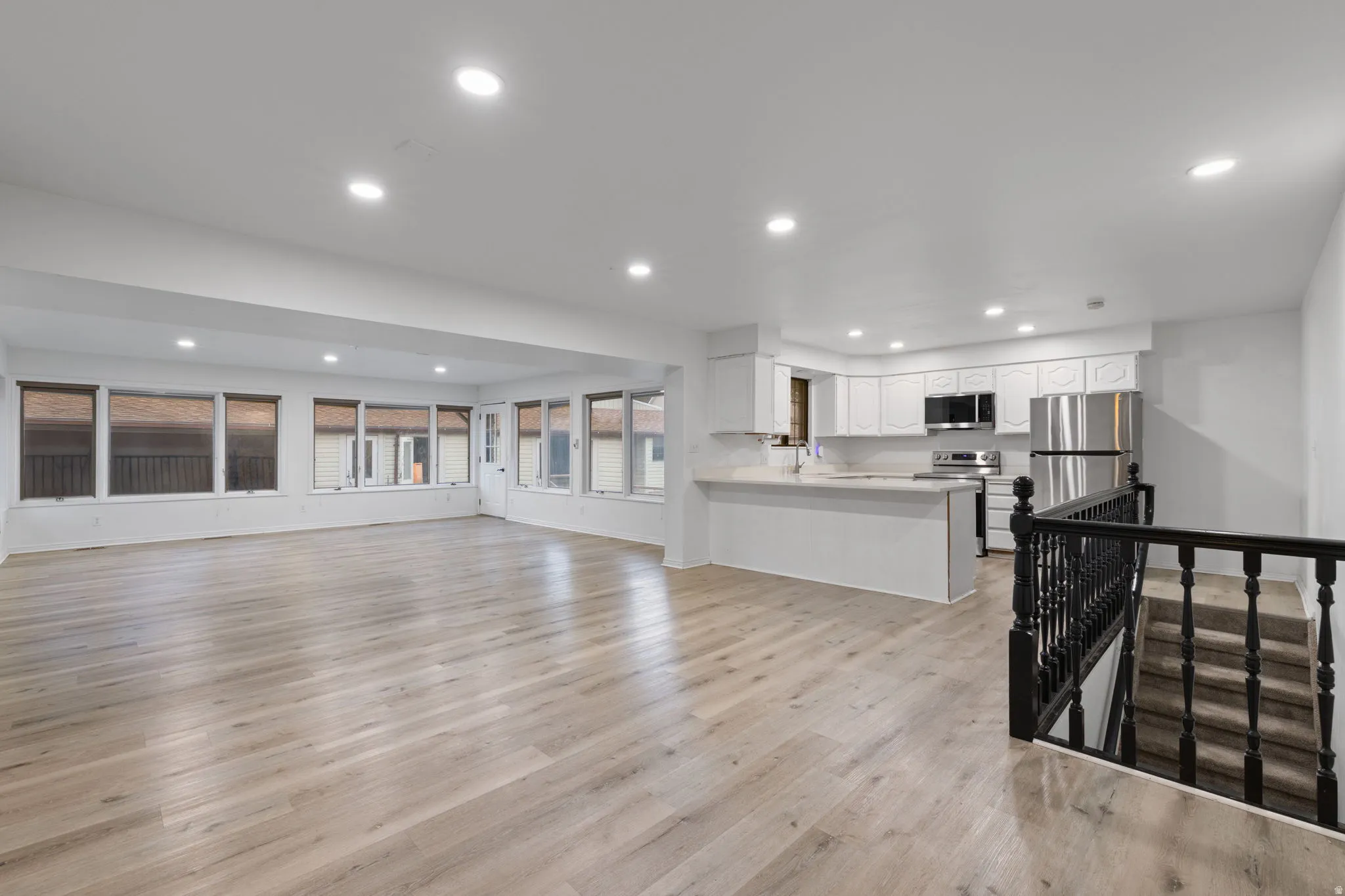 Open-concept living space featuring wood-finish flooring, recessed lighting, and ample natural light from multiple windows