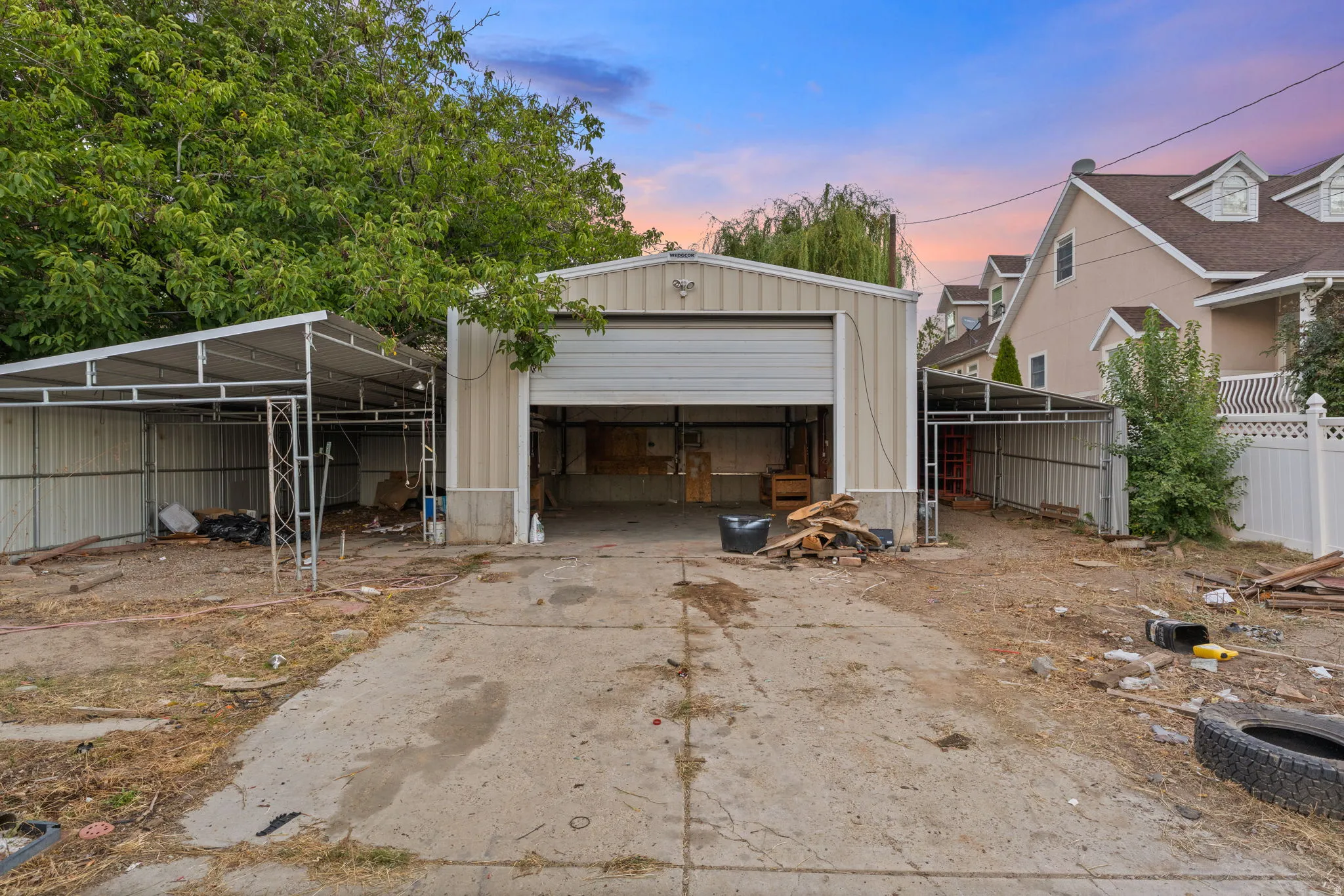 Detached metal garage with roll-up door, featuring two attached metal carports