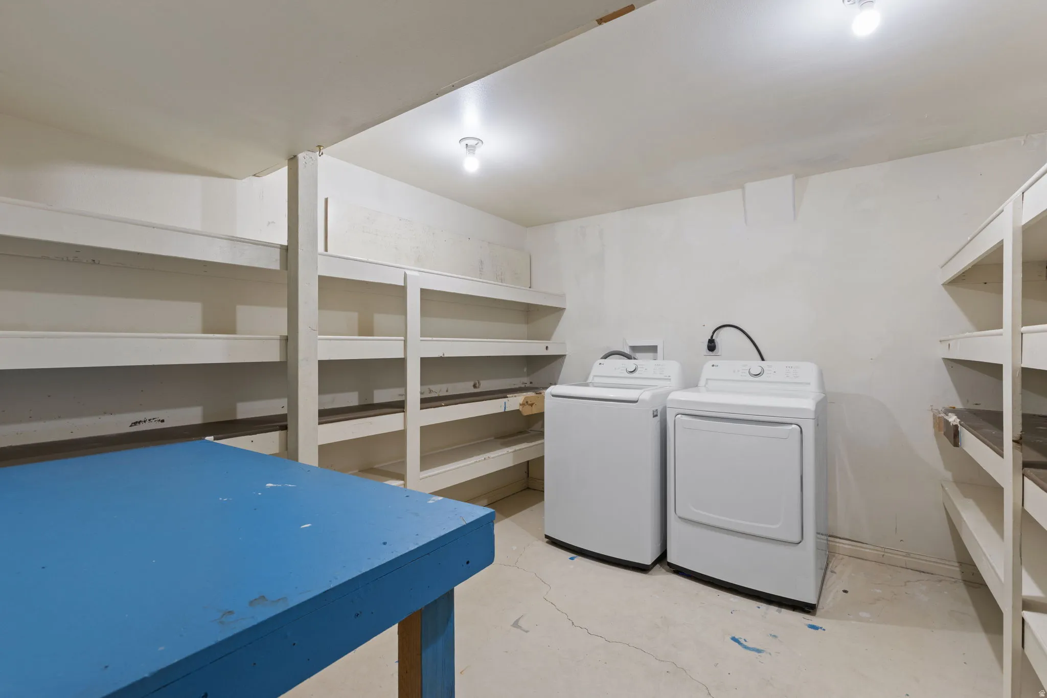 Laundry area with concrete flooring, built-in shelving, and overhead lighting