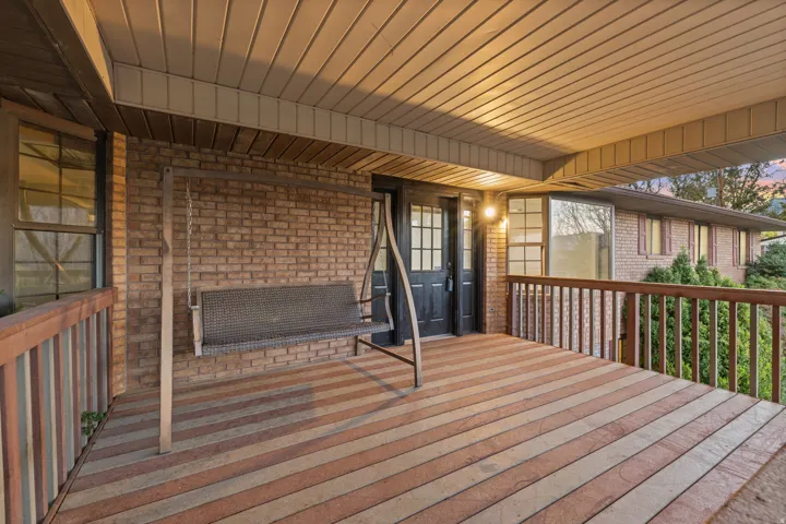 Covered porch with striped wood-finish decking, brick exterior, and wood railing