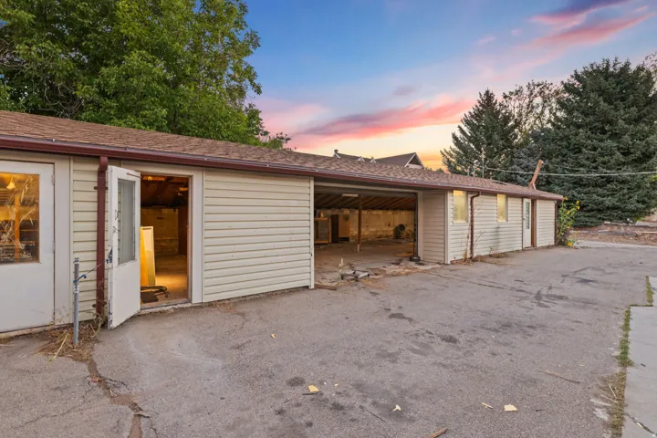 Detached outbuilding with multiple access points, covered parking area, and vinyl siding