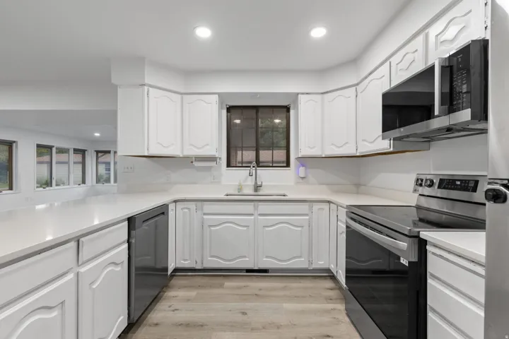 U-shaped kitchen featuring white cabinetry, light-toned countertops, and wood-finish flooring