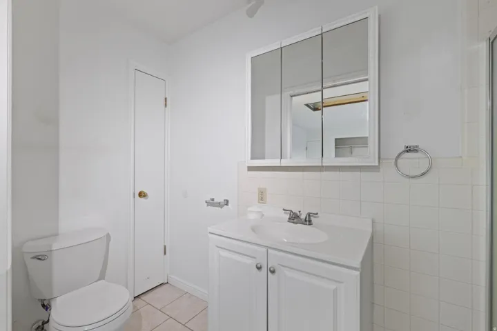 Recessed medicine cabinet, white vanity with integrated sink, chrome faucet, and white wall tile