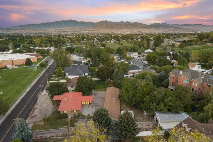 Residential neighborhood with mature trees, mountain backdrop, and adjacent green space