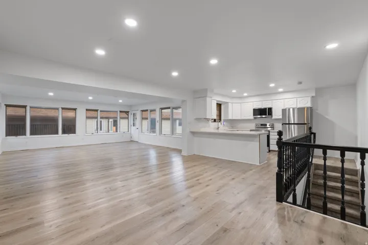 Open-concept living space featuring wood-finish flooring, recessed lighting, and ample natural light from multiple windows