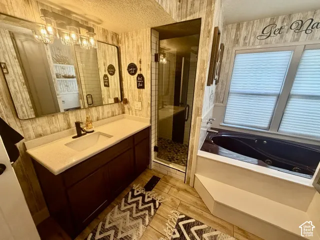 Wood-finish plank wall paneling, a dark wood-finish vanity with a light-toned countertop, a rectangular mirror, a glass-enclosed shower, and a built-in jetted tub
