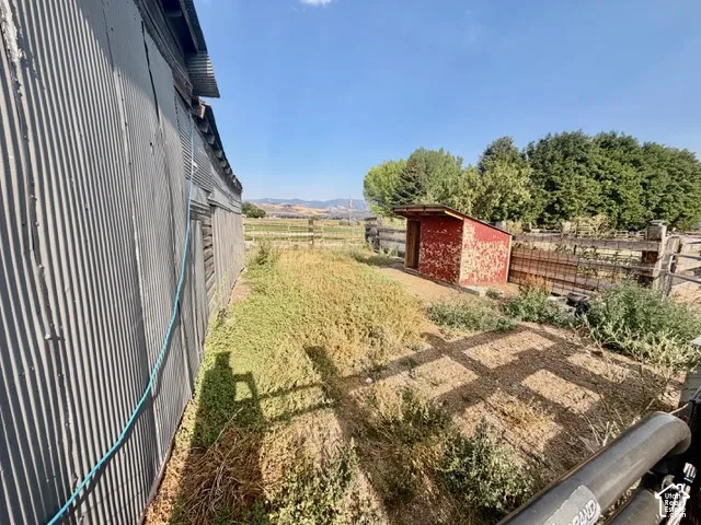 Corrugated metal siding structure with a wood-framed red shed and perimeter fencing
