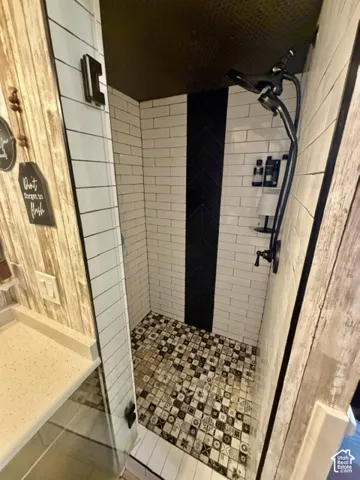 Shower with subway tile walls, patterned floor tile, matte black fixtures, and a glass enclosure