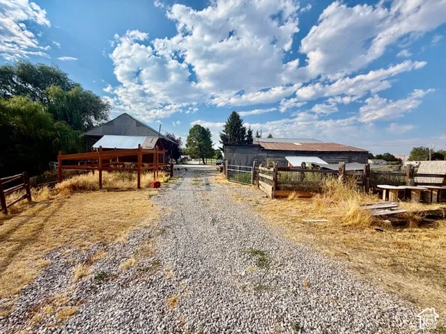 Gravel driveway leading to outbuildings, including a barn with a metal roof and an additional structure with a rusted metal roof