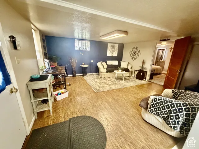 Wood-finish flooring throughout, featuring a recessed window, a single overhead fluorescent light fixture, and a wood-paneled door