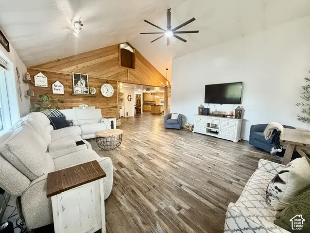 Vaulted ceiling with a contemporary ceiling fan, wood-finish flooring, and a wood-paneled accent wall