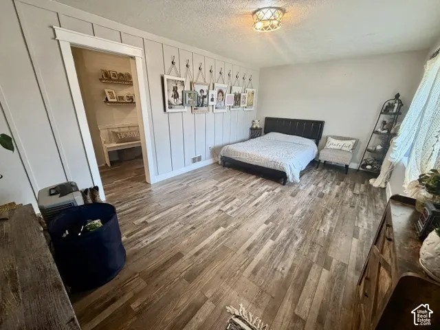 Wood-finish flooring, accent wall with vertical paneling, recessed lighting, and a doorway with trim work