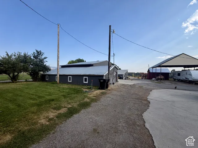 Large outbuilding with a metal roof, multiple windows, and a gravel driveway