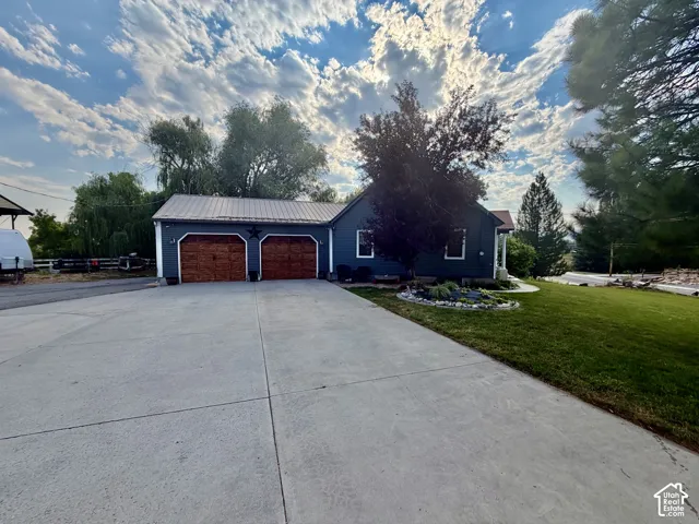 Concrete driveway leading to a residence with a metal roof and two wood-finish garage doors