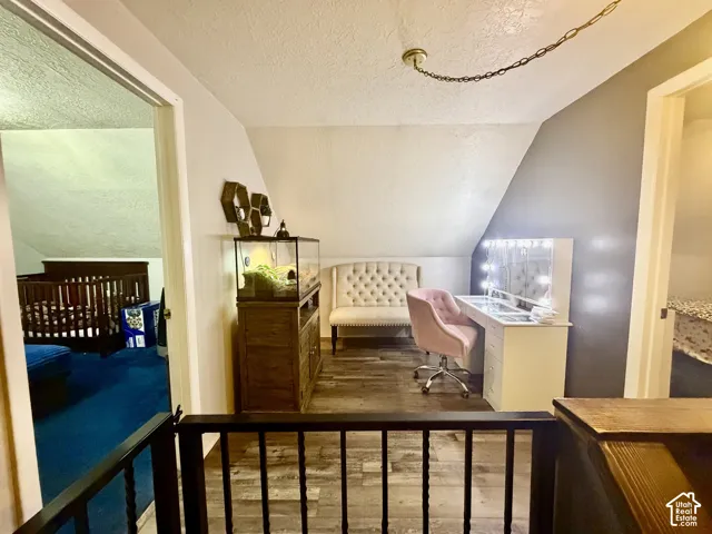 Wood-finish flooring with a decorative railing, ceiling-mounted light fixture, and an angled wall
