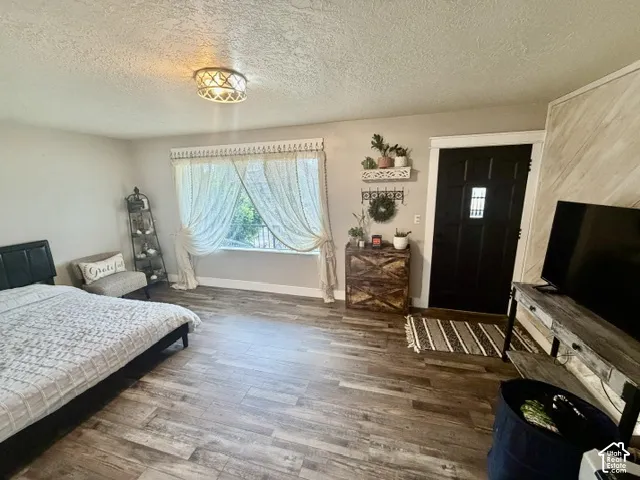 Recessed window with natural light, wood-finish flooring, black paneled entry door, and a decorative ceiling light fixture