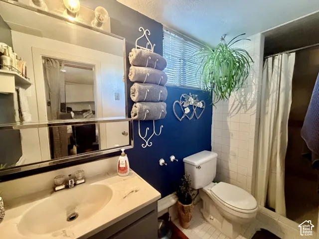 Vanity with an integrated sink and reflective mirror, shower with white tiled surround, and a toilet