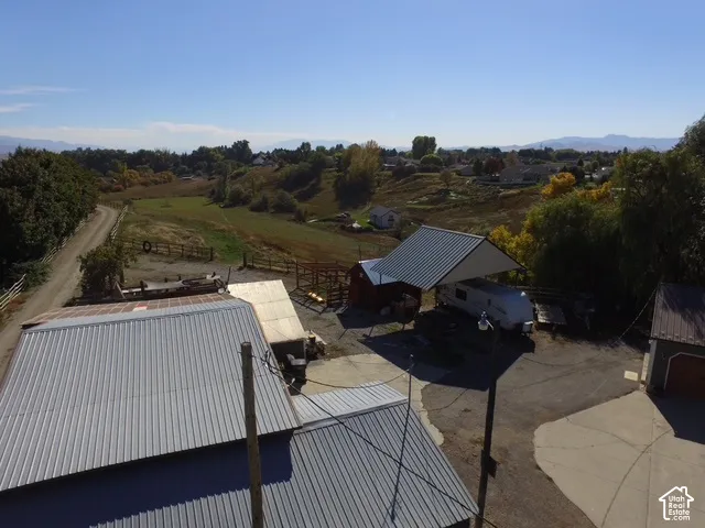 Expansive rural property featuring multiple outbuildings, metal roofs, a covered parking structure, and extensive open land