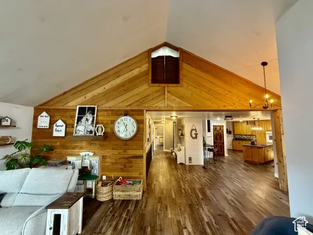 Vaulted ceilings, wood-finish flooring, accent wood paneling, and an open concept layout