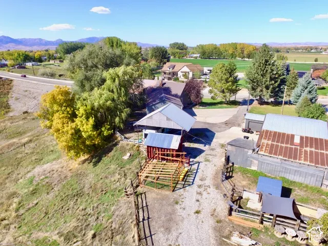 Equestrian property featuring a covered structure with metal fencing, multiple outbuildings including a metal-roof shed, and expansive grounds with mature landscaping