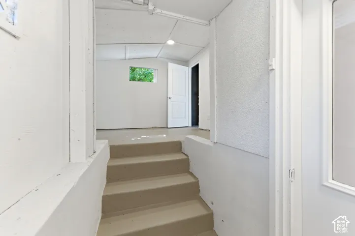 Built-in concrete staircase with painted treads, white-painted walls, and a small window