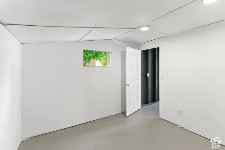 Recessed lighting fixtures, white paneled door, small window, painted concrete flooring