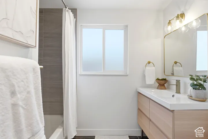 Modern bathroom featuring a wood-finish vanity, integrated sink, and an elegant gold-framed mirror