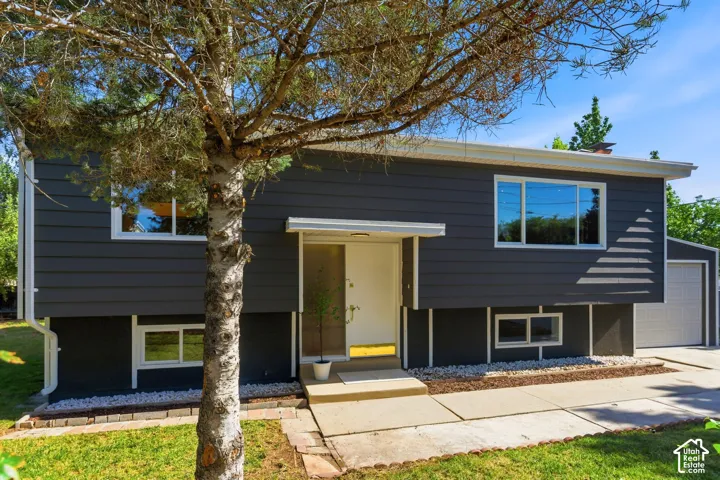 Dark gray exterior siding with white trim, white entry door with a canopy, and a two-car garage