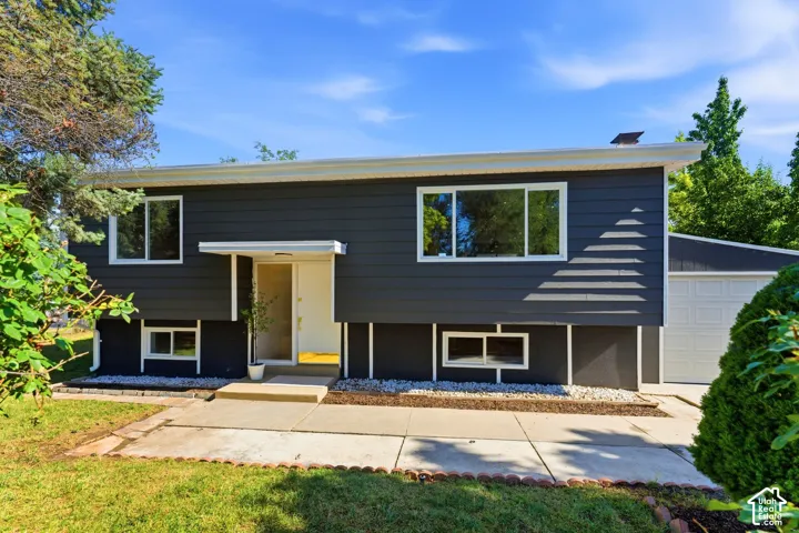 Split-level exterior with dark siding, white trim, and a white entry awning