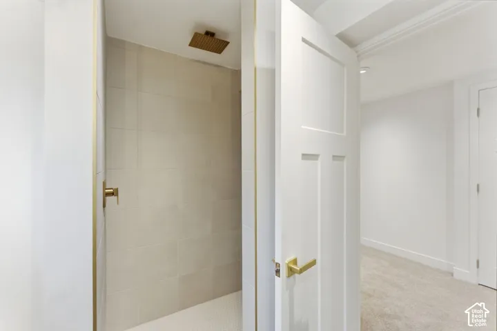 Walk-in shower with large format tile walls, brass rain shower fixture, and a hexagonal mosaic tile floor