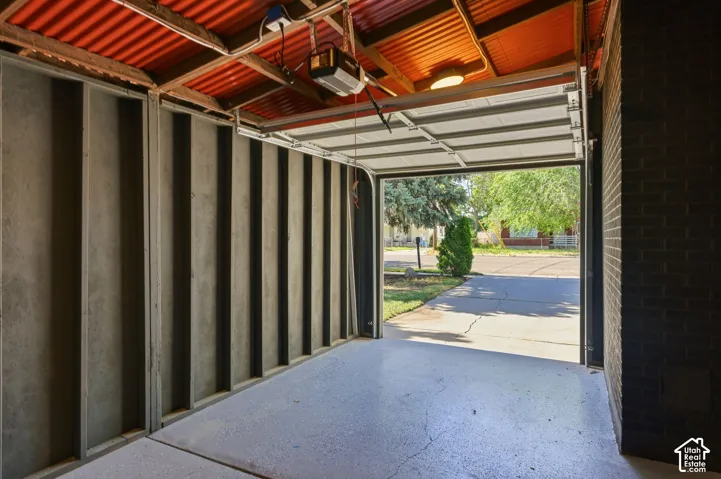 Concrete floor, corrugated metal ceiling, exposed wood beams, automatic garage door opener, brick exterior wall