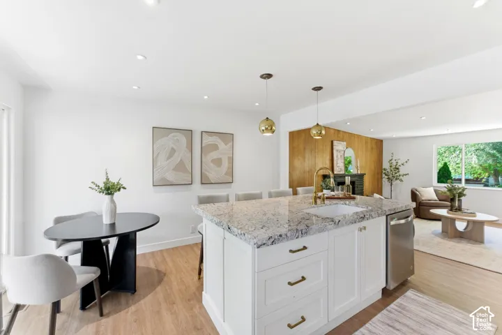 Kitchen island featuring a granite countertop, undermount sink, and stainless steel dishwasher